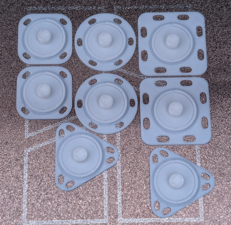 Four white PLA mounting footprint styles printed on a textured plate.